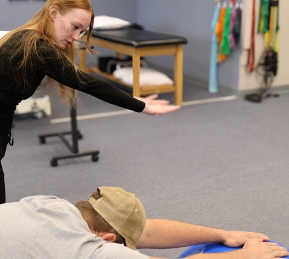 Physical therapist gives patient instructions with an exercise ball